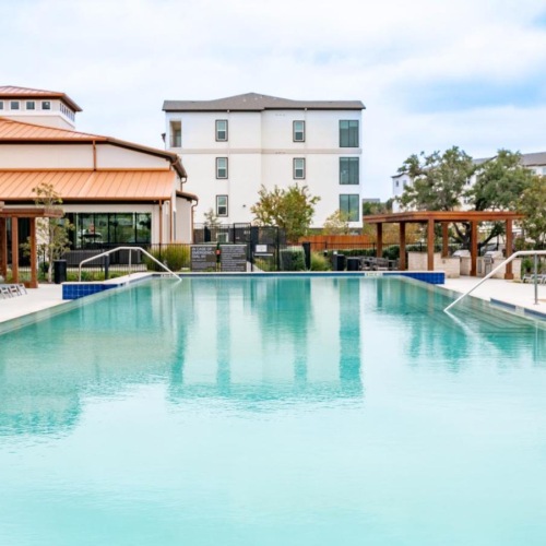 Shimmering resort-style pool a swimming pool with a building in the background
