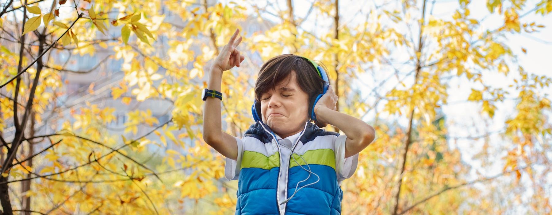 a child wearing headphones and standing in front of trees